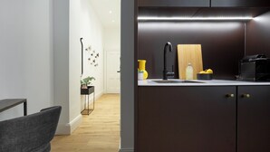 Een moderne keuken met donkere kastjes, een zwarte kraan en een houten snijplank.