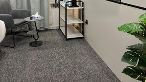 A hotel room with a bed, a desk with a chair, a small table with a tissue box, a shelf unit, and a wall-mounted TV displaying the Netflix logo. - Downtown Suites Orbitnet (Madinah)