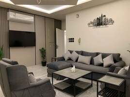 A modern living room with a grey sofa, a coffee table, and a TV mounted on the wall.