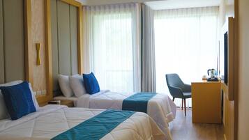 Une chambre d’hôtel avec deux lits, un bureau, une chaise et un téléviseur.