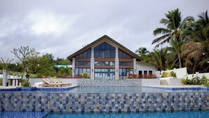 Un hotel moderno con piscina, patio cubierto y palmeras.