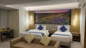 Una habitación de hotel con dos camas, un sofá, un escritorio y un cuadro grande en la pared.