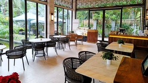 Un restaurante con amplios ventanales, sillas de mimbre y techo de madera.