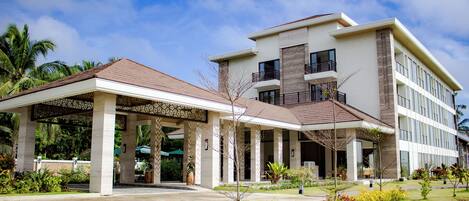 A modern hotel with a covered entrance, multiple floors, and a landscaped garden.
