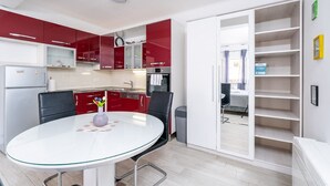 Een moderne keuken met rode en witte kasten, een witte eettafel en een inbouwboekenplank.