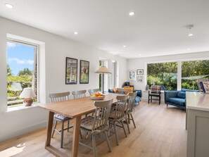 A modern interior with a dining area, seating, and a view of greenery.