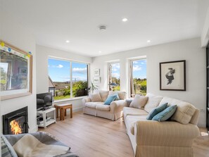 A spacious living room with a fireplace, large windows, and a view of the outdoors.