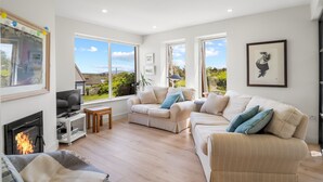 A spacious living room with a fireplace, large windows, and a view of the outdoors.
