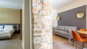 A hotel room with a bed, a nightstand, a lamp, and a stone wall.