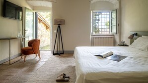 A bedroom with a bed, a chair, a floor lamp, and a window.
