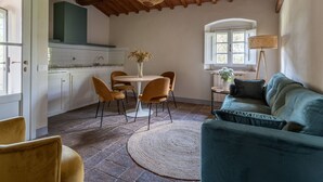 A cozy living room with a green sofa and a dining area with a round table and chairs.