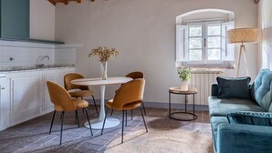 A cozy kitchen with a round table and chairs, a window with a view, and a blue sofa.