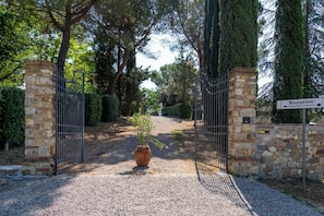A gated entrance with stone pillars, a gravel path, and a reception sign.