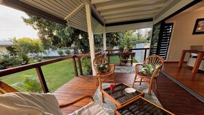 A covered outdoor seating area with wooden furniture and a view of the garden. - Charming 2-bedroom house in welcoming Papeete with WiFi, AC (Papeete)