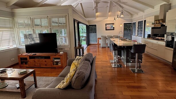 A spacious living area with a large sofa, a TV, and a kitchen in the background. - Charming 2-bedroom house in welcoming Papeete with WiFi, AC (Papeete)