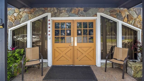 A stone facade entrance with a wooden double door, two chairs, and a doormat. - Calm & Spacious Retreat • Family-Ready Escape (Plant City)