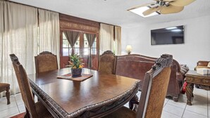 A conference room with a large wooden table, leather chairs, a ceiling fan, a TV, and a window with curtains. - Calm & Spacious Retreat • Family-Ready Escape (Plant City)