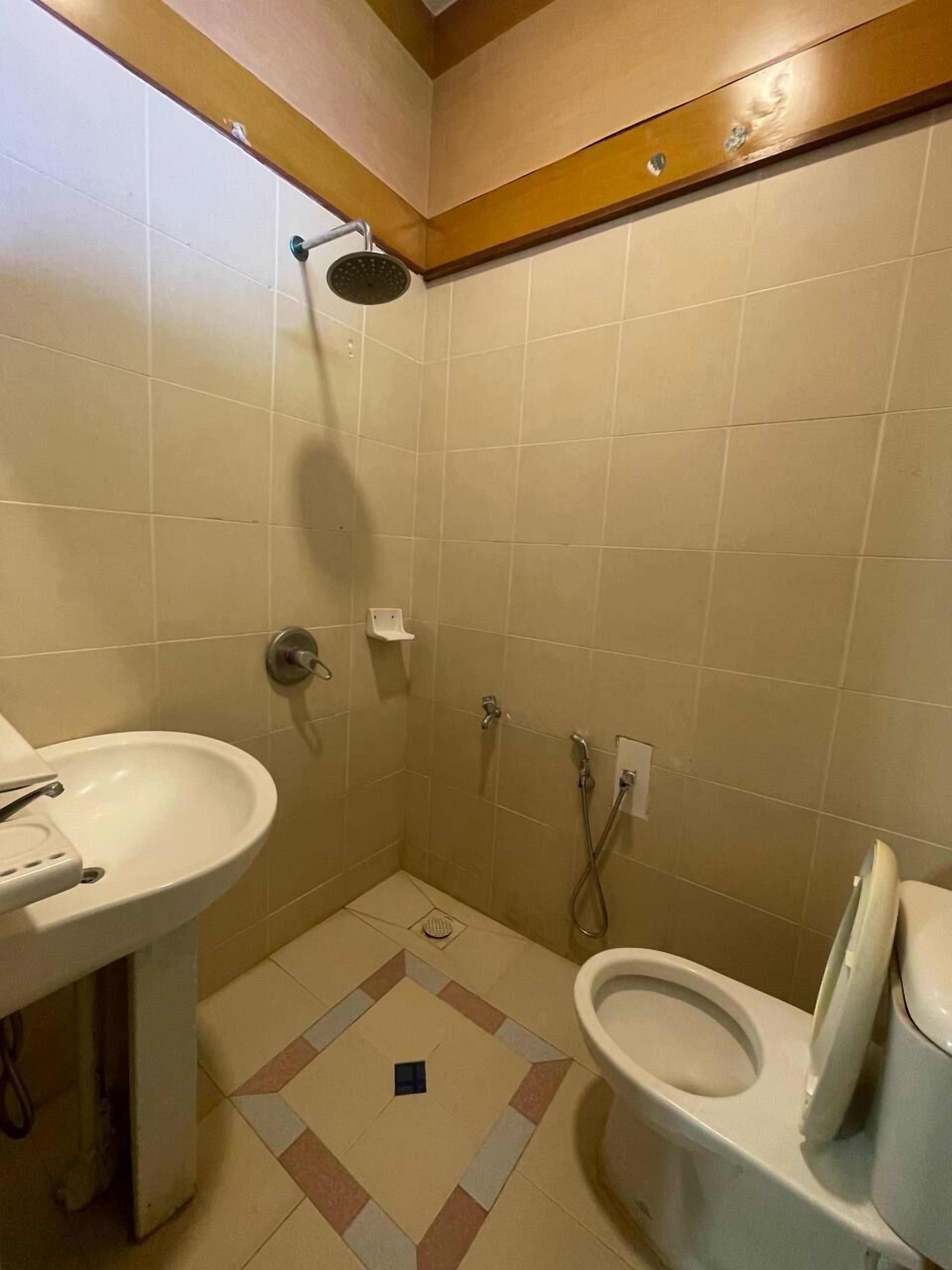Un baño pequeño con azulejos, que incluye una ducha, un lavamanos y un inodoro.
