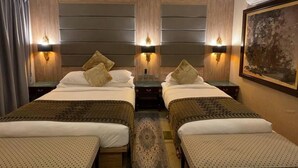 A hotel room with two beds, a small table, and a nightstand. - Suite Sharilla (Pulau Perhentian Kecil)
