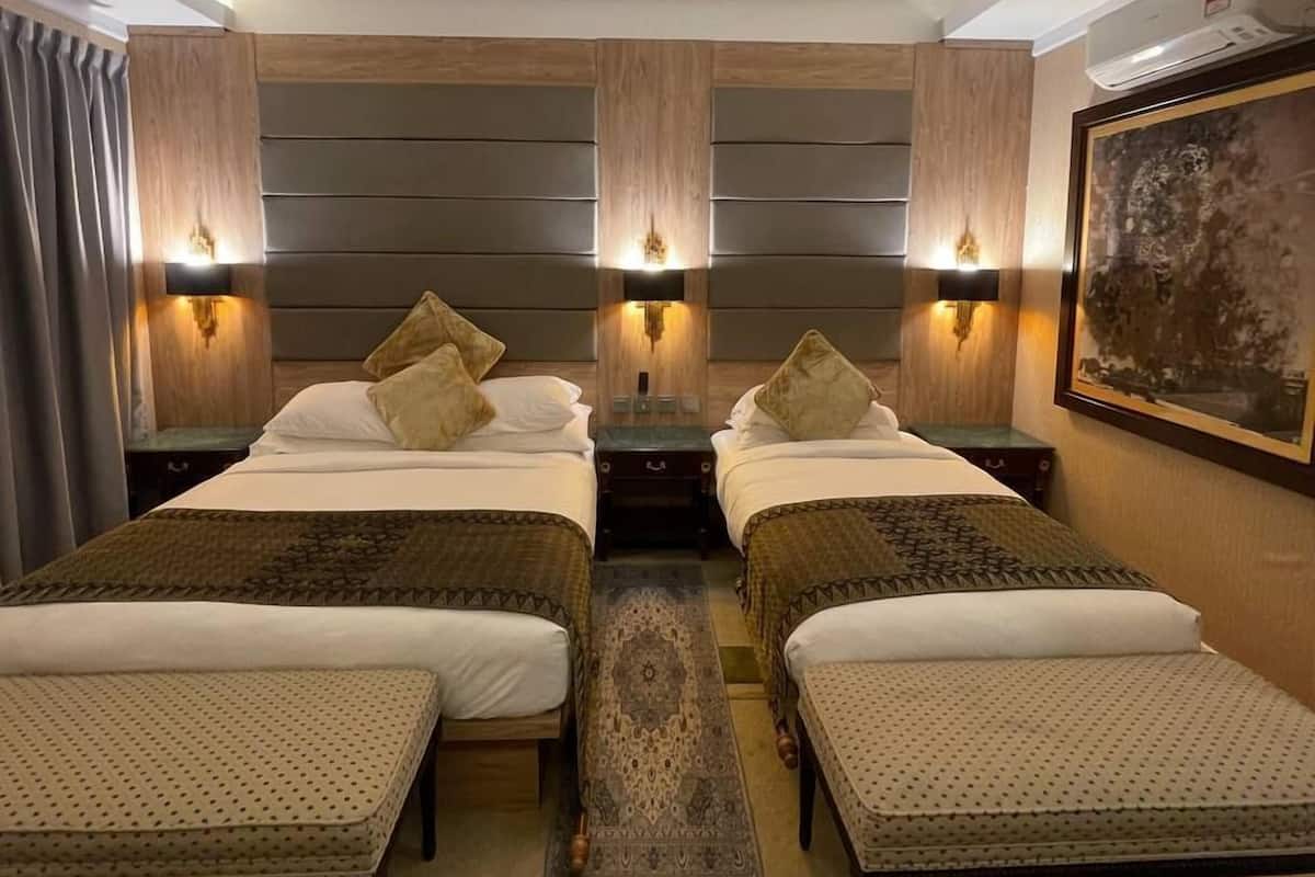 A hotel room with two beds, a small table, and a nightstand.