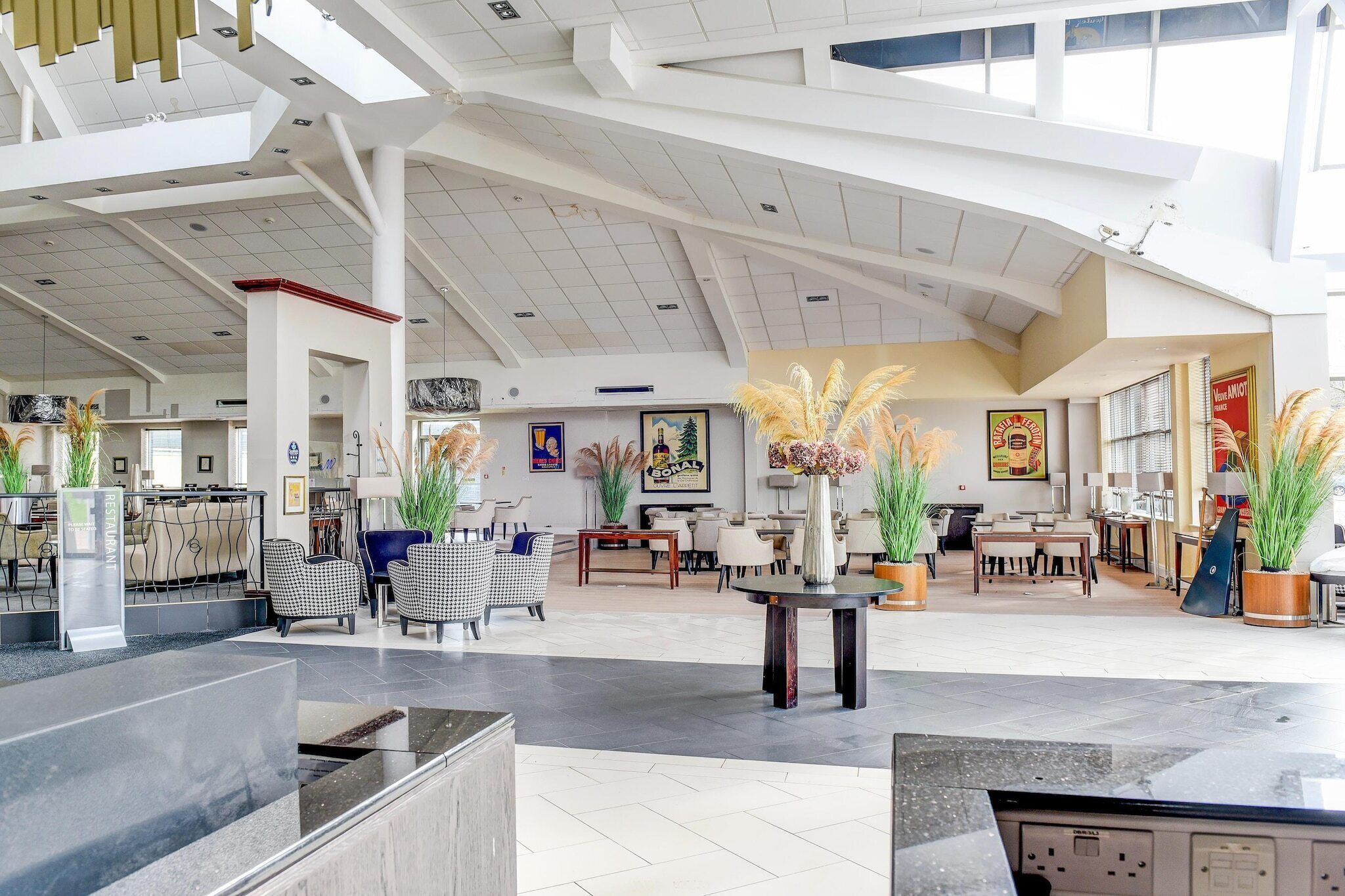 A spacious lobby with high ceilings, modern furniture, and decorative plants.
