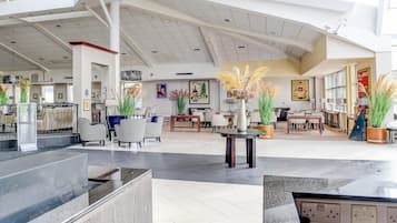 A spacious lobby with high ceilings, modern furniture, and decorative plants.
