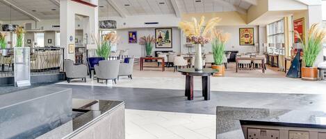 Um hall amplo com pé direito alto, mobiliário moderno e plantas decorativas.
