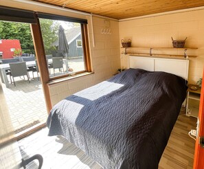 A bedroom with a bed, a window, a wooden ceiling, and a view of the outside. - Cosy holiday house near child friendly beach (Bogense)