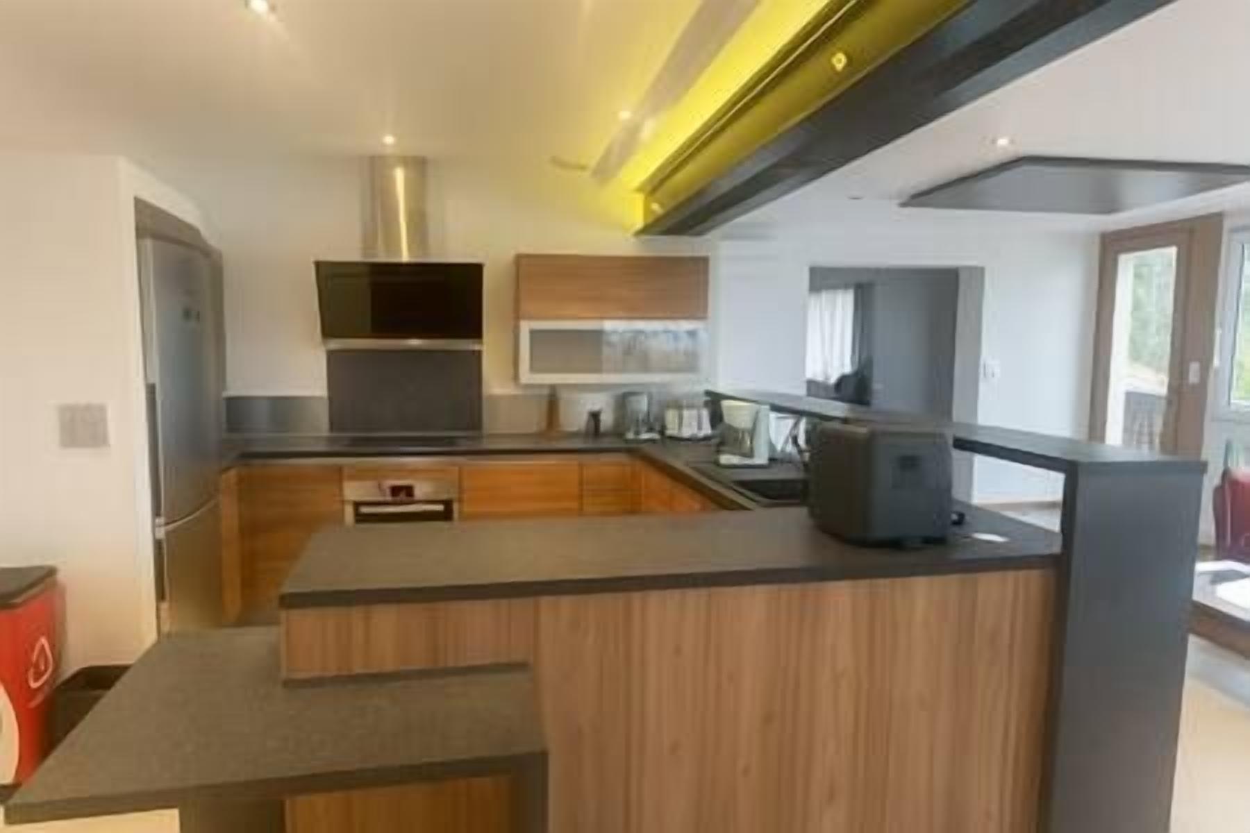 Une cuisine moderne dotée d’un îlot central, d’appareils électroménagers intégrés et d’une grande fenêtre.