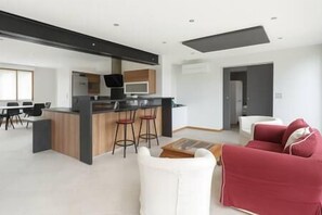 Un espacio habitable moderno con área de cocina, comedor y un sofá rojo.