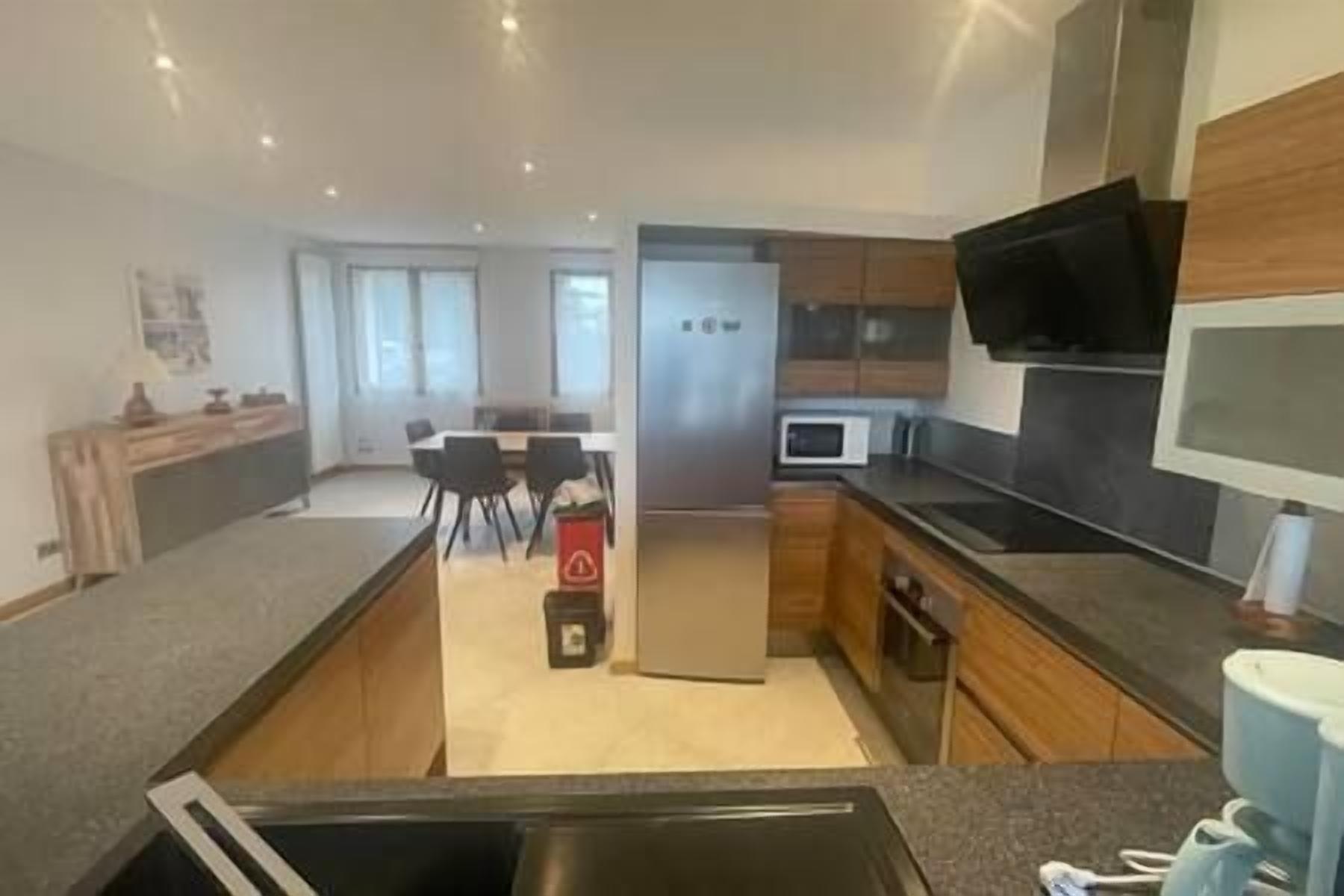 Una cocina moderna con una isla central, electrodomésticos integrados y una zona de comedor con sillas.