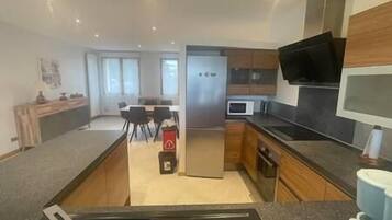 Una cocina moderna con una isla central, electrodomésticos integrados y una zona de comedor con sillas.