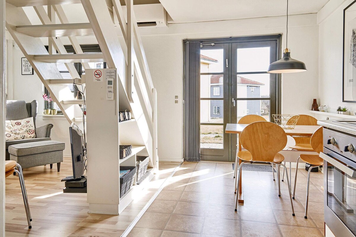 Una cocina moderna con comedor, sillas de madera y una escalera.