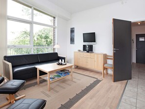 Un salon moderne avec un canapé en cuir noir, une table basse en bois, un téléviseur et un meuble.