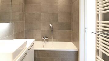 A modern bathroom with a bathtub, a mirror, and a shower.