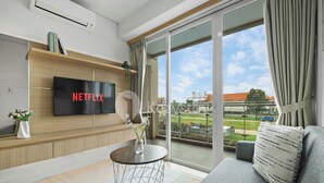 Ein modernes Wohnzimmer mit einem Flachbildfernseher, einem runden Couchtisch und einem Sofa.