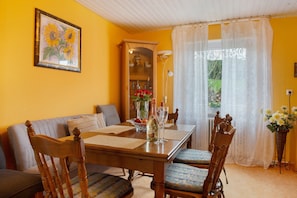 A dining area with a wooden table, chairs, a sofa, and a cabinet with glass doors. - Apartment 'Hofer' with Shared Garden and Wi-Fi (Kalkofen)