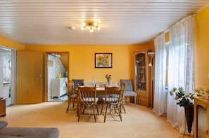 A dining area with a wooden table and chairs, a painting on the wall, and a cabinet with glass doors. - Apartment 'Hofer' with Shared Garden and Wi-Fi (Kalkofen)