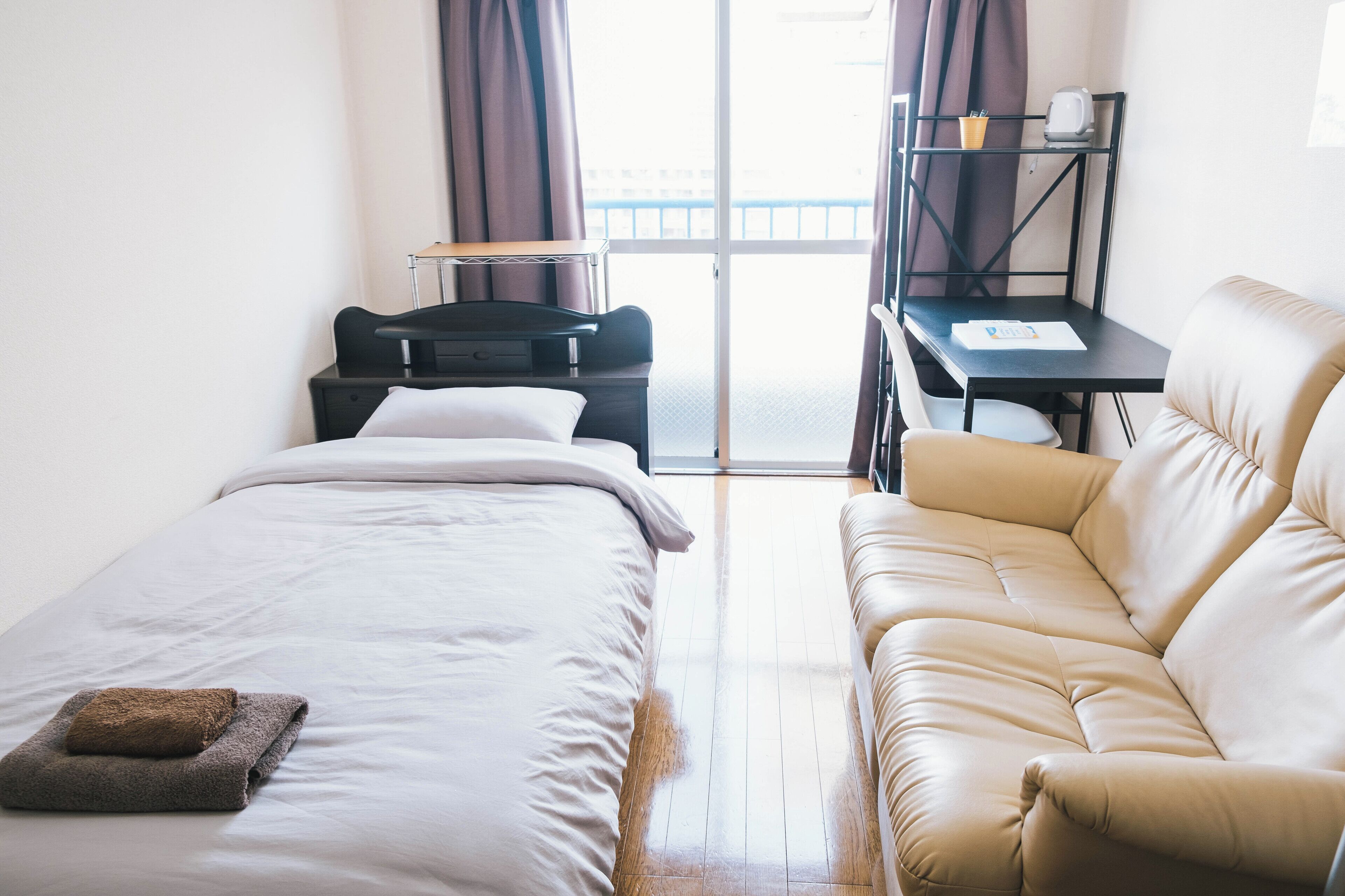 Ett hotellrum med en säng, en soffa, ett skrivbord med en stol och ett fönster med gardiner.