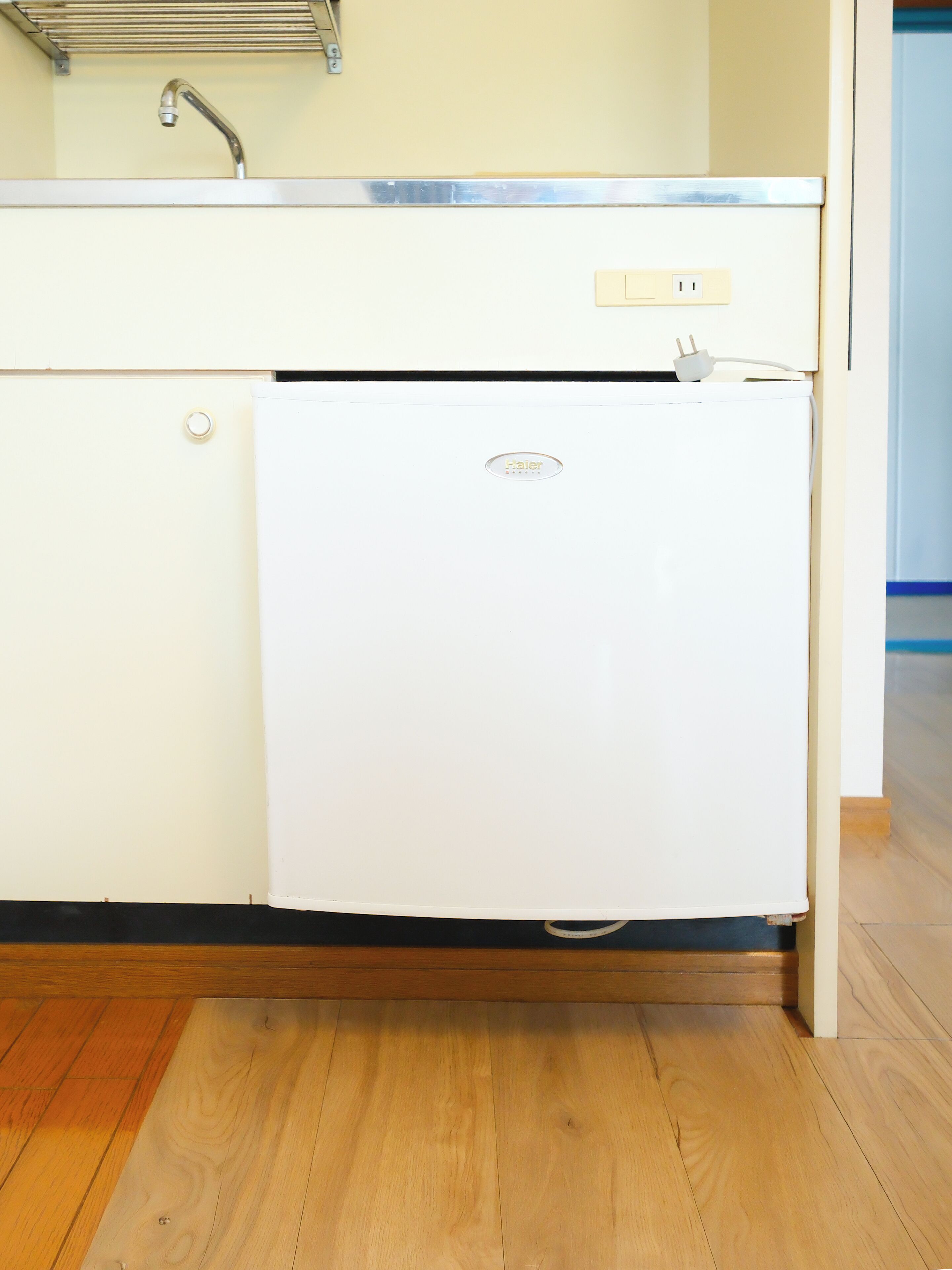 A compact kitchen with a white refrigerator, a sink, and a faucet.