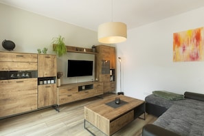 Un salon moderne avec une table basse en bois, un téléviseur à écran plat et un canapé.