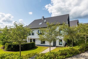 Une maison à deux étages, avec un toit recouvert de tuiles, une antenne parabolique et une petite fenêtre.