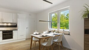Una cocina moderna con armarios blancos, horno empotrado y zona de comedor con una mesa dispuesta para cuatro personas.
