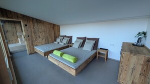 Una camera da letto moderna con due letti, pareti in legno e un comodino di legno.