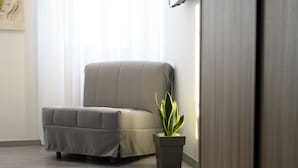 Une pièce moderne avec un canapé gris, une plante en pot et un plancher en bois.