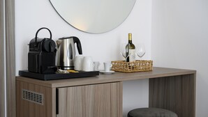 Une petite cuisine équipée d’une machine à café, d’une bouilloire et d’un verre à vin, le tout posé sur un plan de travail en bois.
