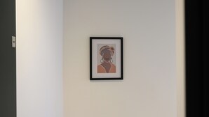 Ein gerahmtes Kunstwerk an einer schlichten Wand in einem Flur.