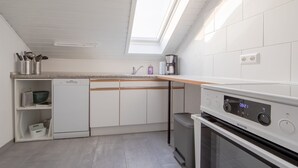 Una cocina moderna con armarios blancos, lavavajillas, cafetera y horno empotrado.