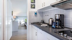 A modern kitchen with a built-in stove, a coffee maker, and a kettle. - Apartment 'Schwarzwaldblick D App 10 with Pool, Sauna, Mountain View, Wi-Fi (Schönwald im Schwarzwald)