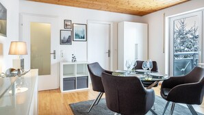 A modern dining area with a wooden ceiling, a glass table, and dark chairs. - Apartment 'Schwarzwaldblick D App 10 with Pool, Sauna, Mountain View, Wi-Fi (Schönwald im Schwarzwald)